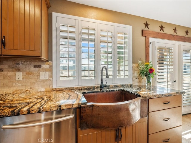 kitchen with a sink, stone countertops, tasteful backsplash, and dishwasher