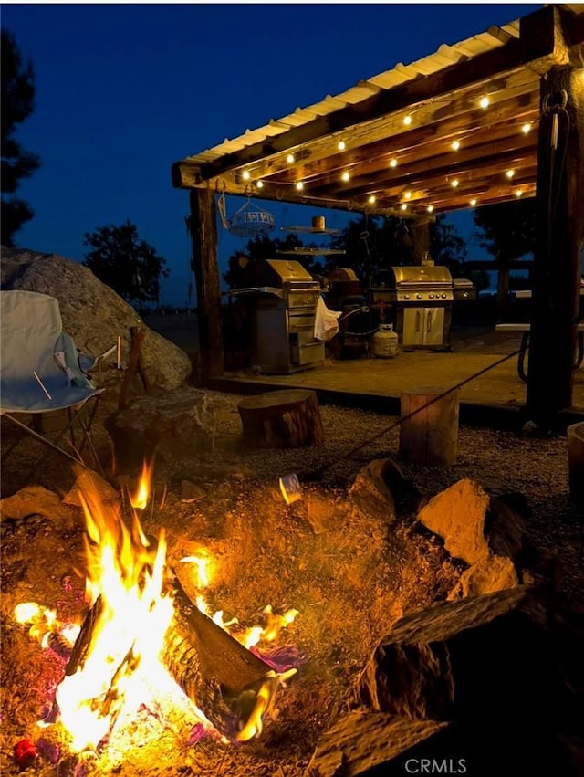 patio at twilight featuring area for grilling and a fire pit