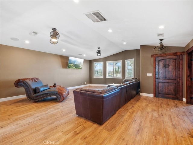 interior space with visible vents, baseboards, light wood-style flooring, and vaulted ceiling