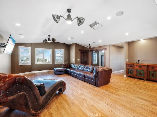 living area featuring vaulted ceiling, visible vents, baseboards, and wood finished floors