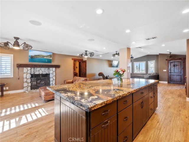 kitchen featuring visible vents, plenty of natural light, a stone fireplace, and light wood-style flooring