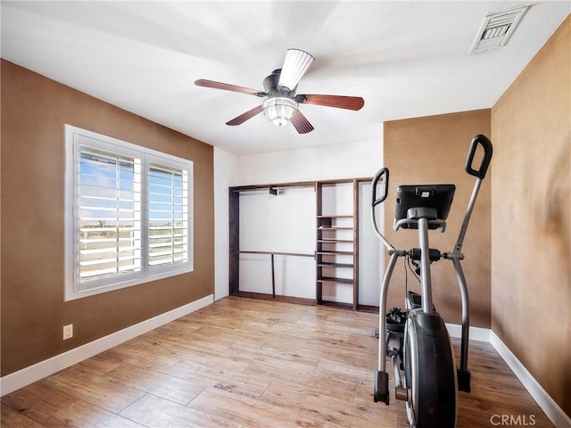 workout area featuring visible vents, light wood-style flooring, baseboards, and ceiling fan