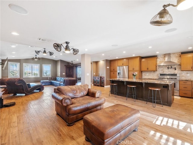 living room featuring visible vents, baseboards, light wood-type flooring, lofted ceiling, and recessed lighting