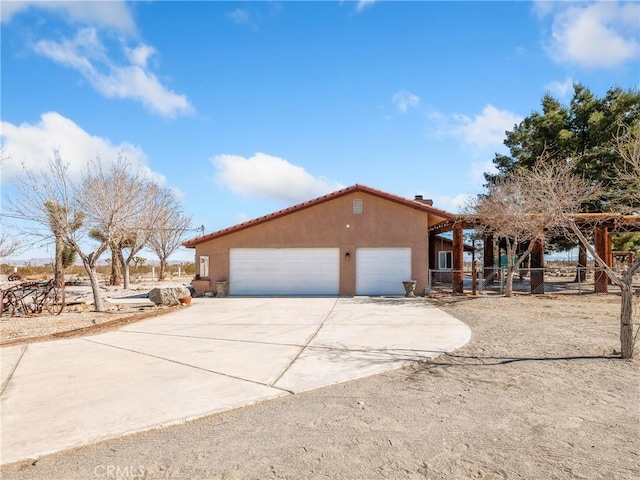 view of front of property with driveway, a chimney, stucco siding, a garage, and a tile roof