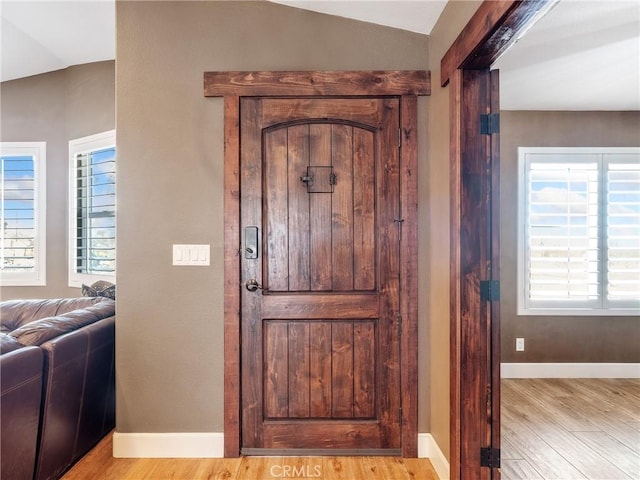 entrance foyer featuring baseboards, wood finished floors, and vaulted ceiling