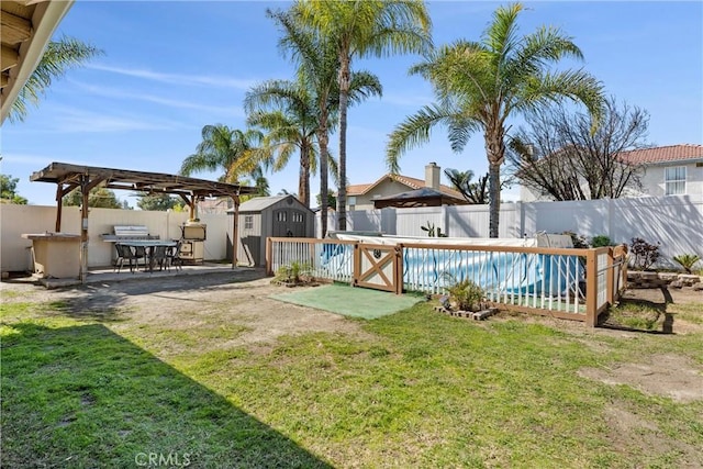 view of yard featuring an outdoor structure, a storage unit, a fenced backyard, and a fenced in pool