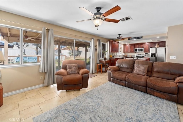 living area featuring light tile patterned flooring, visible vents, ceiling fan, and baseboards