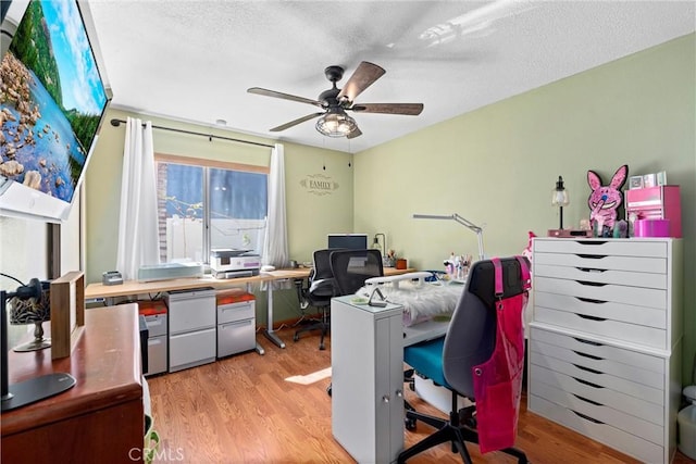 office area with light wood-type flooring, a textured ceiling, and a ceiling fan