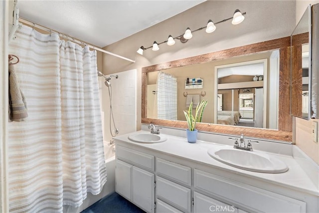 full bath featuring double vanity, shower / bathtub combination with curtain, ensuite bath, and a sink