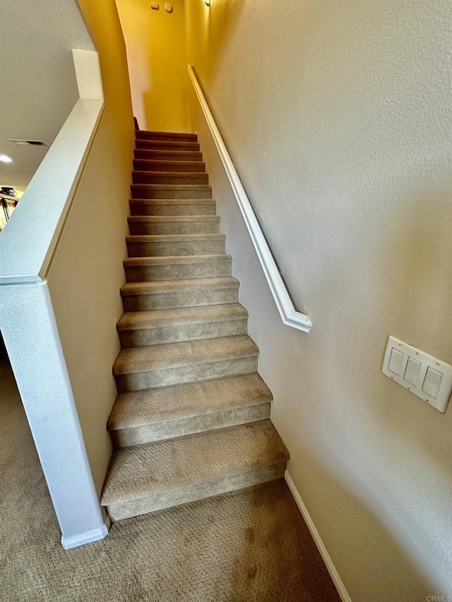 staircase featuring carpet flooring and baseboards