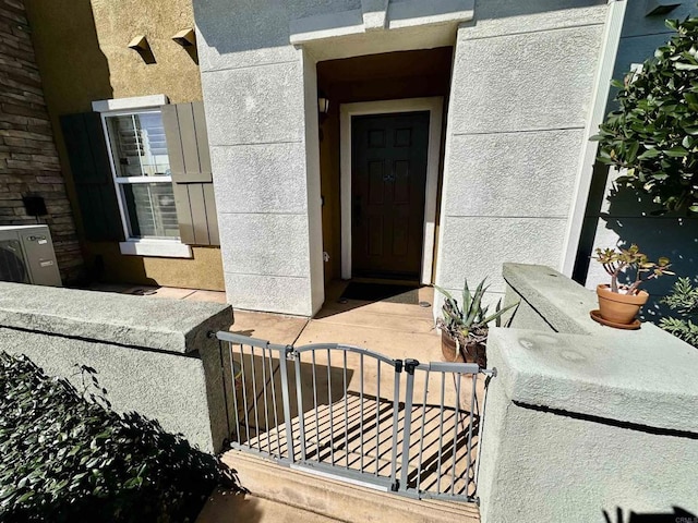 doorway to property featuring a gate and stucco siding