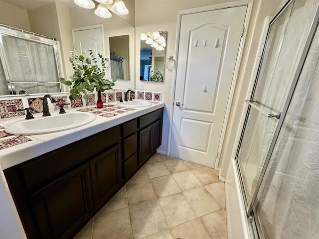 bathroom with a shower with door, tile patterned floors, double vanity, and a sink