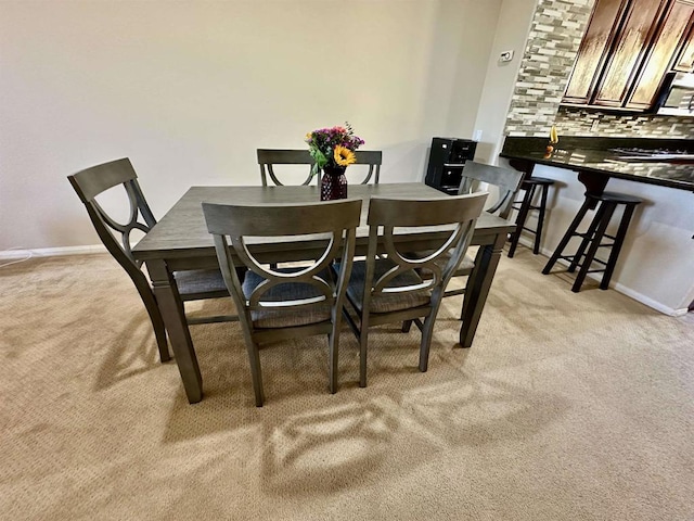 dining room with baseboards and light carpet