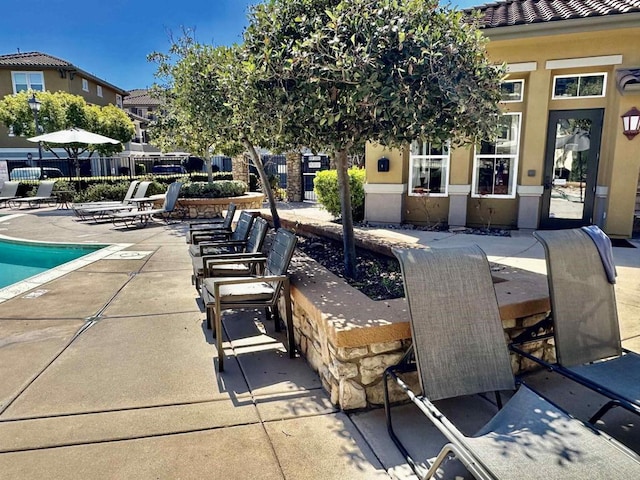 view of patio with a community pool and fence