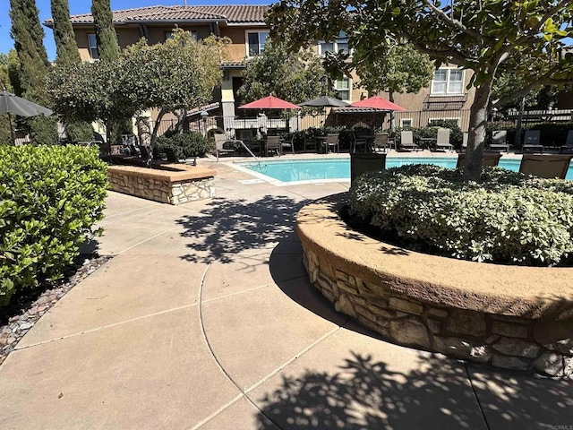 pool with a patio area and fence