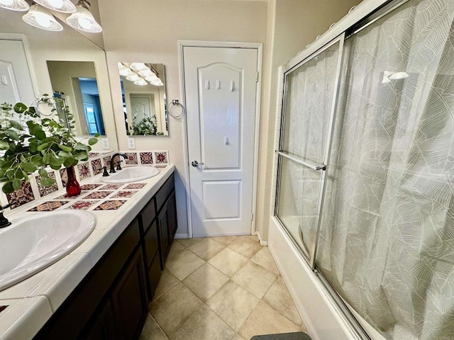 full bathroom featuring double vanity, combined bath / shower with glass door, and a sink