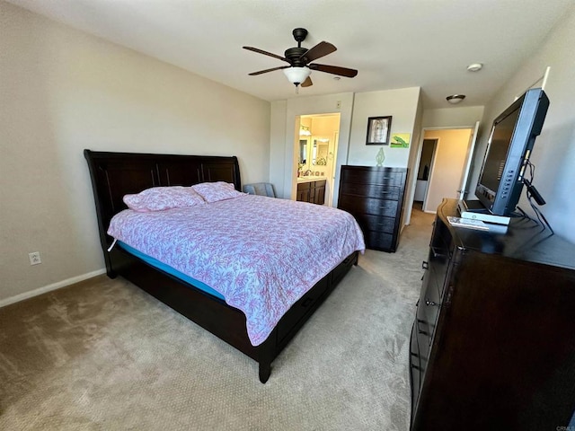 bedroom featuring light carpet, ceiling fan, ensuite bath, and baseboards