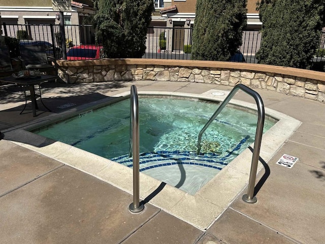 view of pool with a hot tub and fence