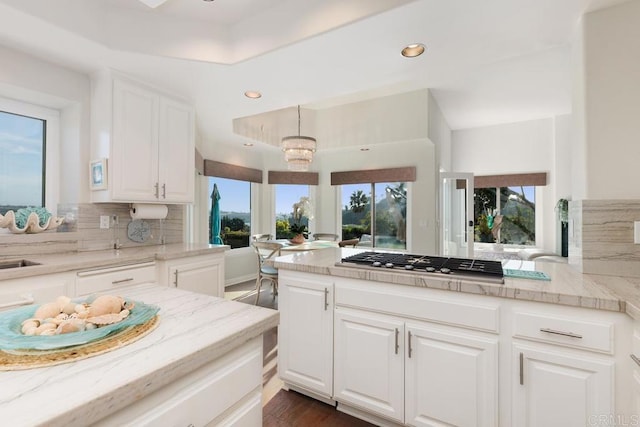 kitchen with white cabinetry, a healthy amount of sunlight, tasteful backsplash, and stainless steel gas cooktop