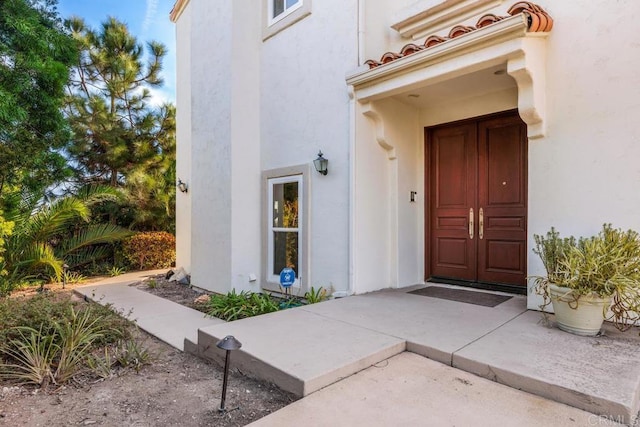 entrance to property featuring a tile roof and stucco siding