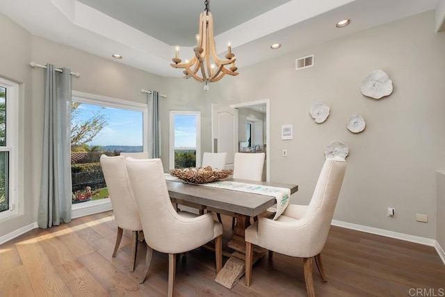 dining room featuring visible vents, a raised ceiling, wood finished floors, recessed lighting, and baseboards