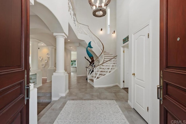 entryway with stairway, baseboards, a high ceiling, decorative columns, and arched walkways