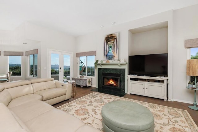 living area with a wealth of natural light, dark wood finished floors, and a high end fireplace