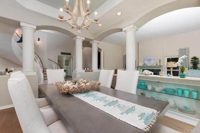 dining area with stairway, decorative columns, recessed lighting, arched walkways, and a notable chandelier