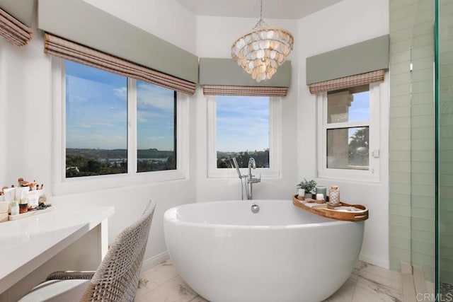 bathroom with an inviting chandelier, a soaking tub, baseboards, and marble finish floor