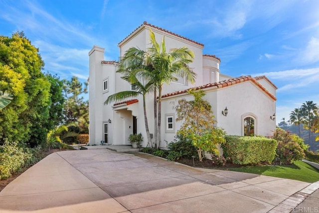 mediterranean / spanish home with a tiled roof and stucco siding