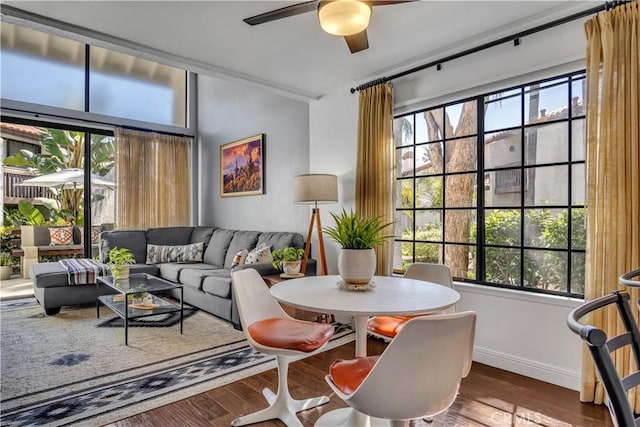 living area featuring baseboards, ceiling fan, and wood finished floors