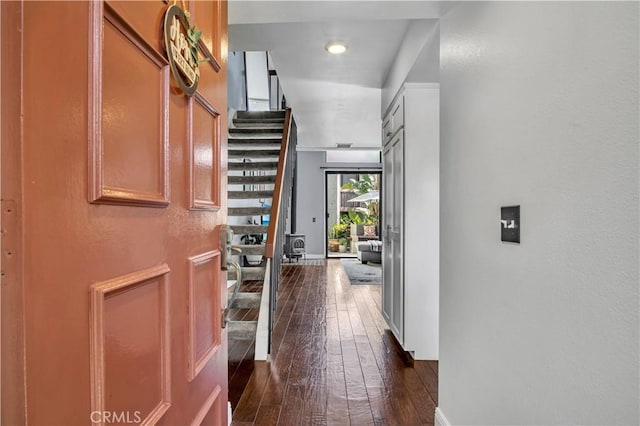 corridor featuring stairway, baseboards, and dark wood-style flooring