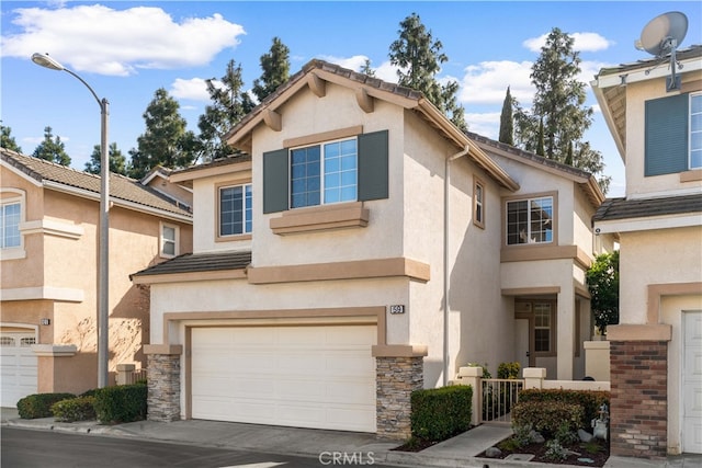 view of front of house featuring a tiled roof, concrete driveway, stucco siding, stone siding, and an attached garage