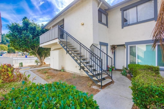 exterior space with stairway and stucco siding