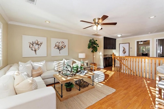 living area with visible vents, ornamental molding, recessed lighting, light wood-style floors, and a ceiling fan