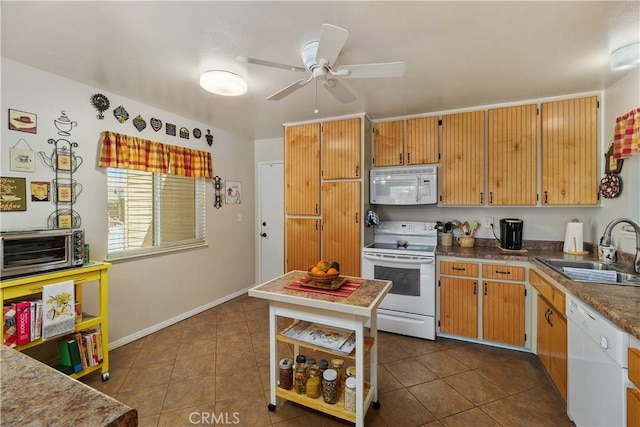 kitchen featuring white appliances, baseboards, ceiling fan, a sink, and dark tile patterned floors