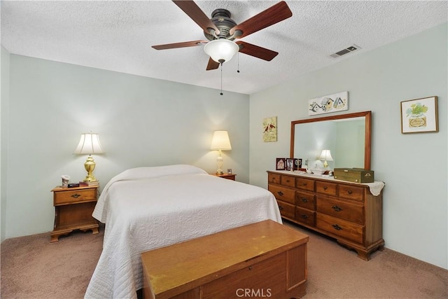 bedroom featuring visible vents, light carpet, a textured ceiling, and ceiling fan