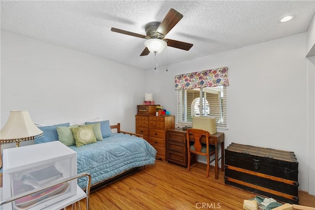 bedroom with ceiling fan, a textured ceiling, and wood finished floors