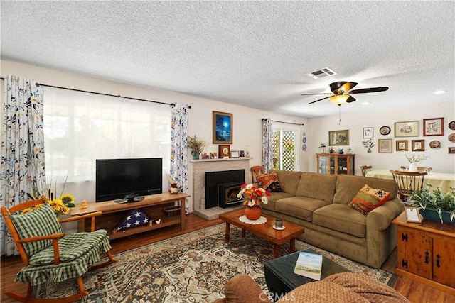 living room with visible vents, a textured ceiling, ceiling fan, and wood finished floors