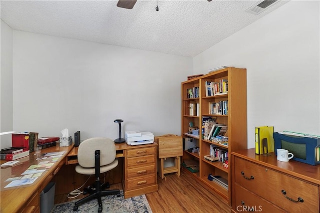 home office with ceiling fan, visible vents, a textured ceiling, and light wood-style flooring