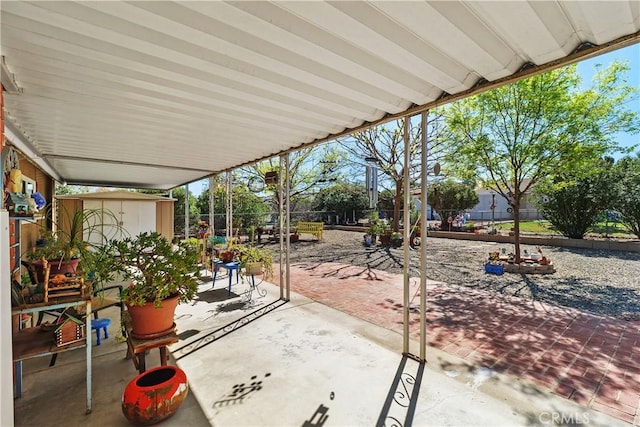 view of patio featuring a storage shed, a fenced backyard, and an outbuilding