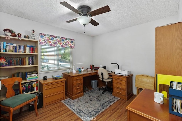 home office with light wood-style floors, ceiling fan, and a textured ceiling