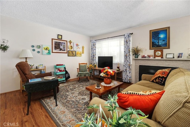 living area with baseboards, a textured ceiling, and wood finished floors