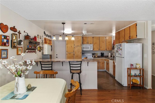 kitchen featuring visible vents, ceiling fan, a peninsula, white appliances, and a sink