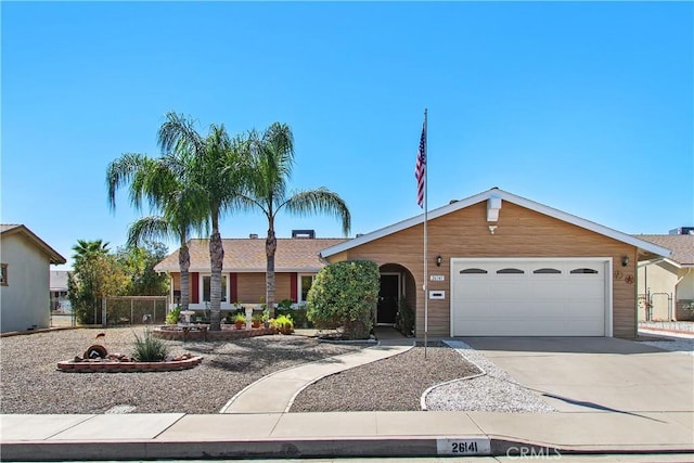 ranch-style home featuring driveway, an attached garage, and fence