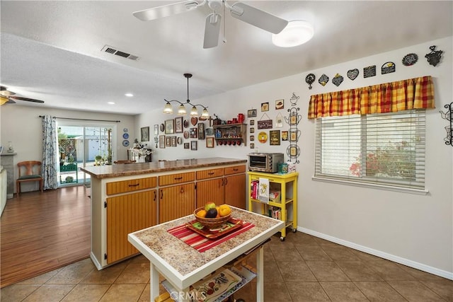 kitchen featuring tile patterned floors, visible vents, a peninsula, light countertops, and ceiling fan