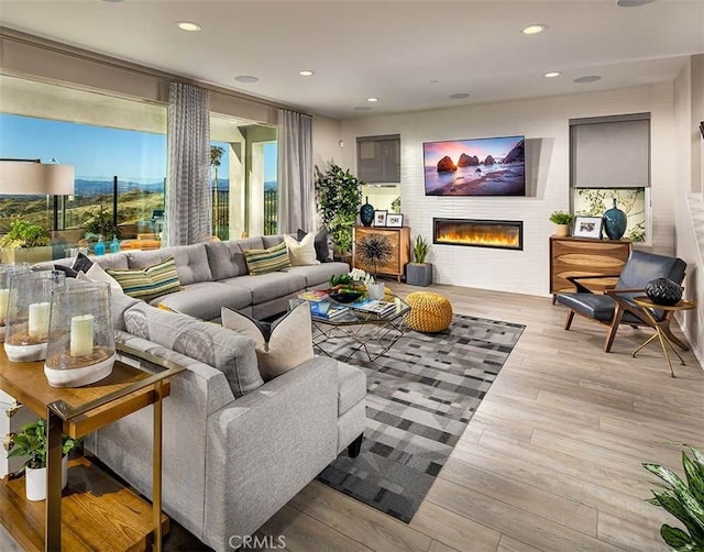 living room featuring a glass covered fireplace, wood finished floors, and recessed lighting