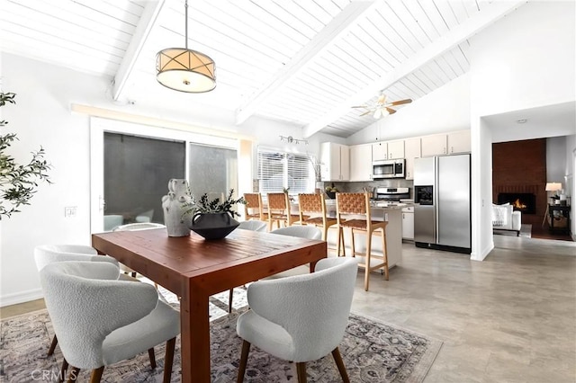 dining space featuring beam ceiling, high vaulted ceiling, and a large fireplace