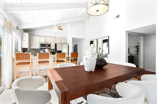 dining area with lofted ceiling with beams, a ceiling fan, and visible vents