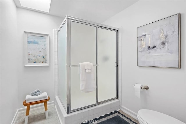 full bathroom featuring baseboards, toilet, and a stall shower